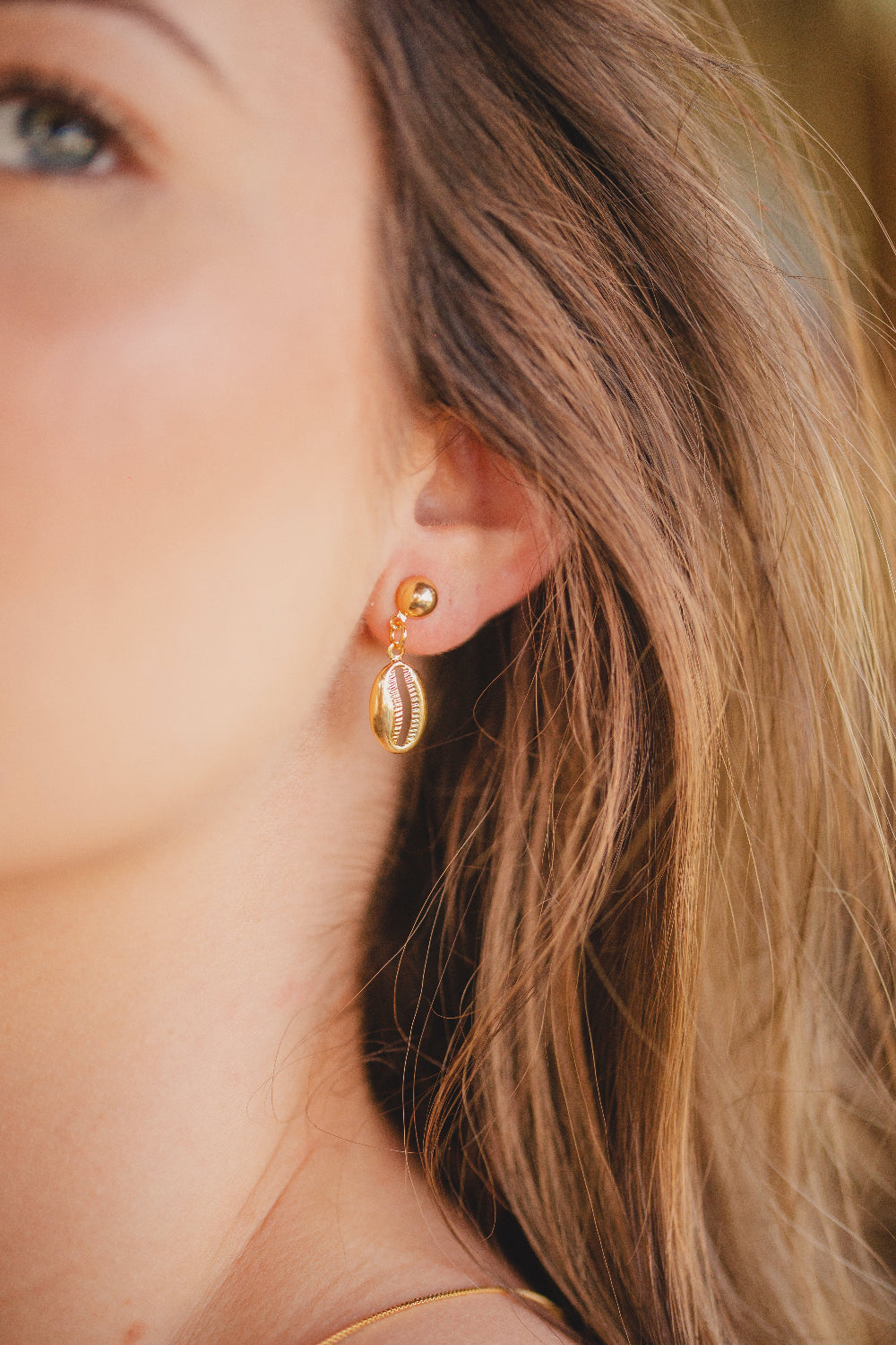 BRINCO LISO COM PINGENTE DE BÚZIOS FOLHEADO A OURO 18K