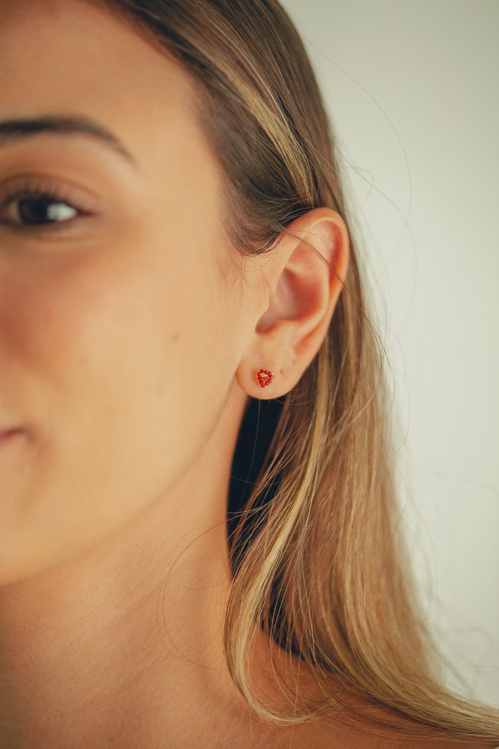 BRINCO MINI CORAÇÃO VAZADO COM STRASS VERMELHA FOLHEADO A OURO 18K